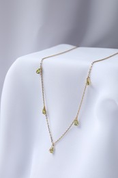 Photo of Stylish presentation of necklace on white cloth