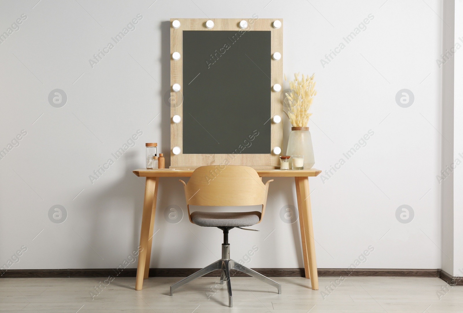 Photo of Dressing table with stylish mirror, dried reeds and other decorative elements. Interior design