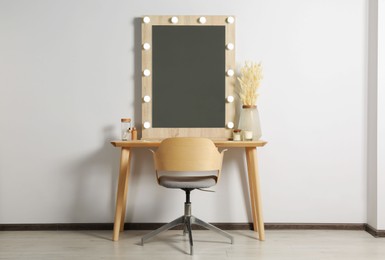 Dressing table with stylish mirror, dried reeds and other decorative elements. Interior design