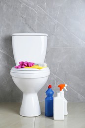 Photo of Toilet bowl and different cleaning supplies indoors