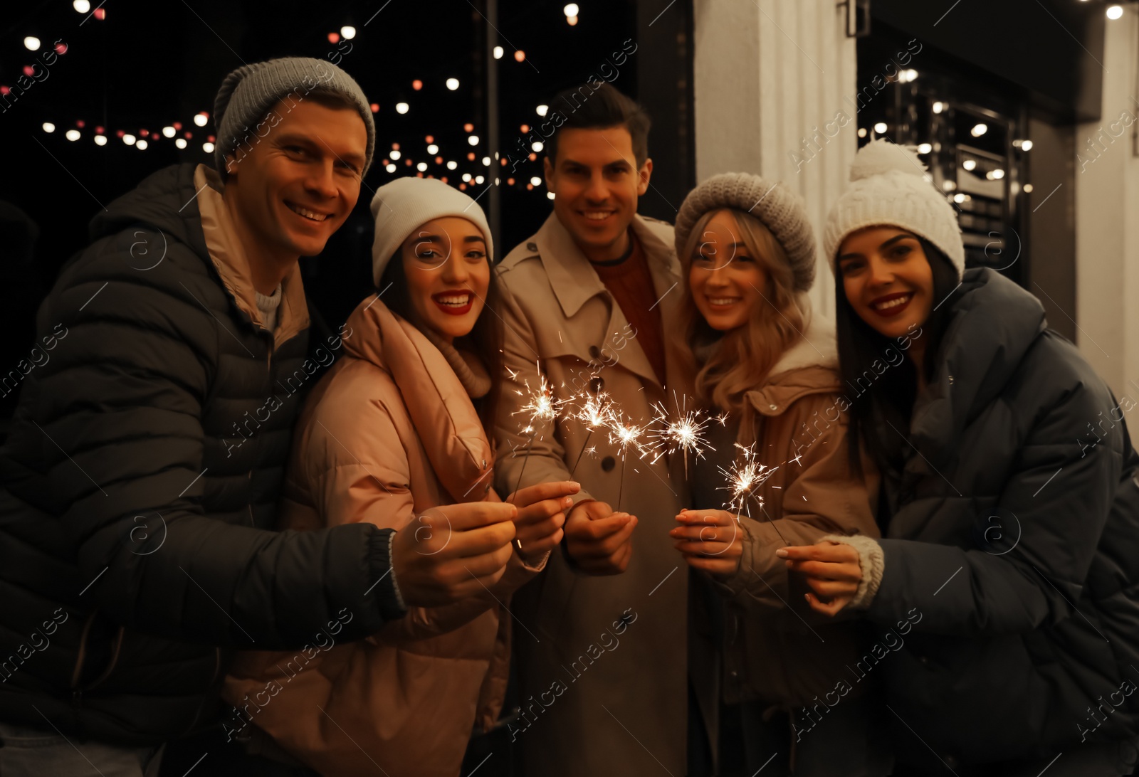 Photo of Group of people holding burning sparklers outdoors