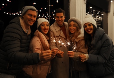 Group of people holding burning sparklers outdoors