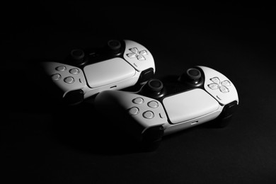 Two wireless game controllers on black background