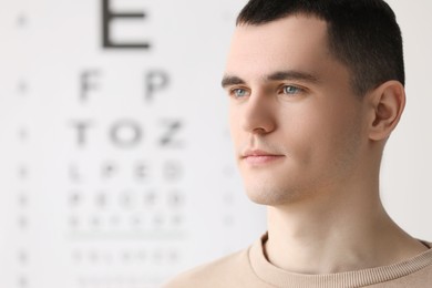 Photo of Portrait of young man against vision test chart