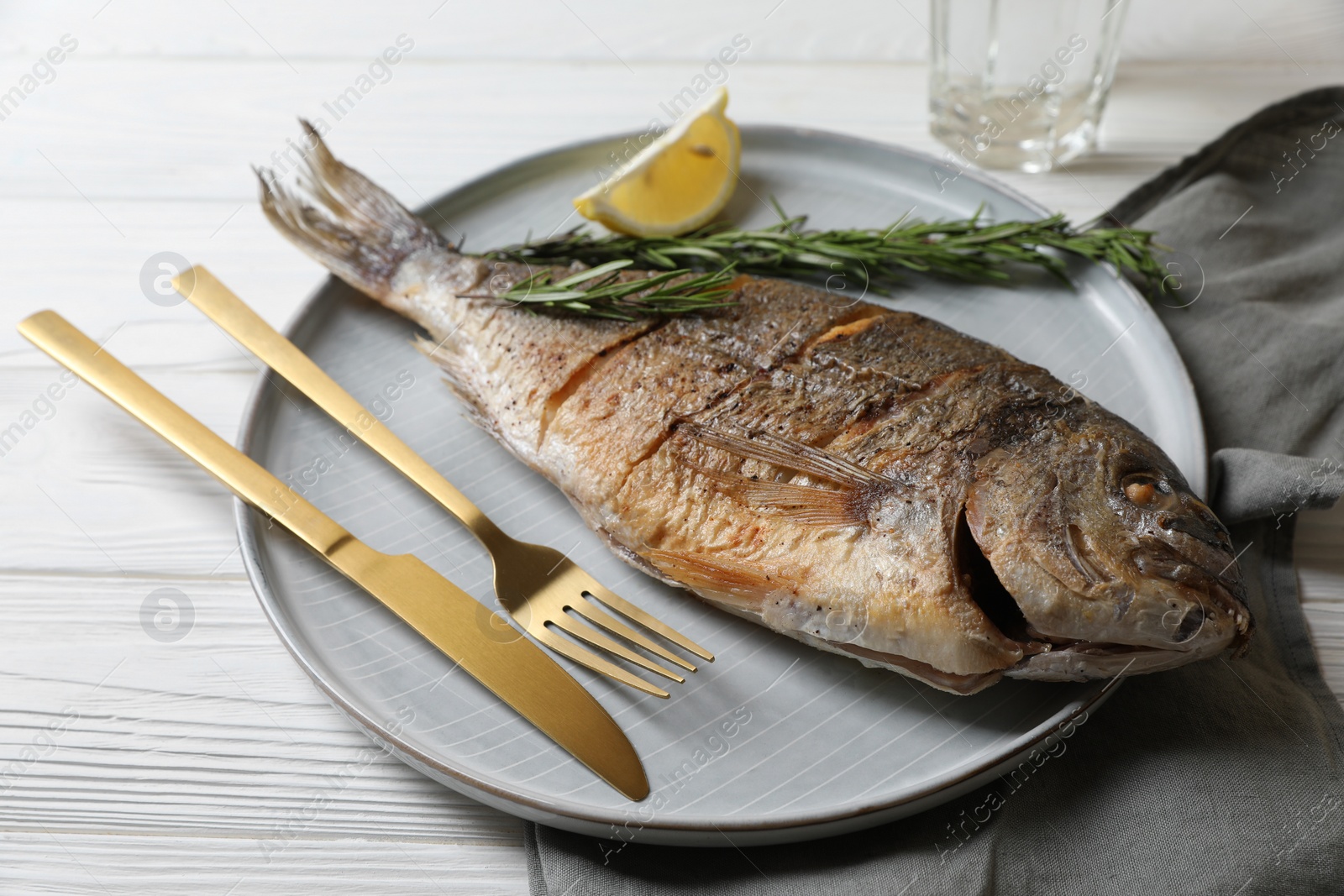 Photo of Delicious baked fish served on white wooden table, closeup. Seafood