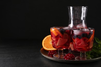 Photo of Delicious Red Sangria and ingredients on black table, space for text