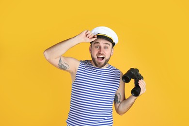 Photo of Emotional sailor with binoculars on yellow background