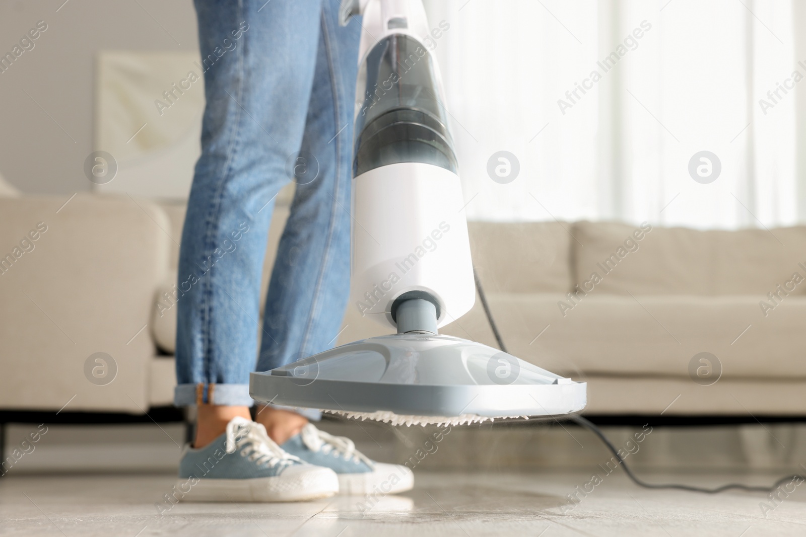 Photo of Woman cleaning floor with steam mop at home, closeup