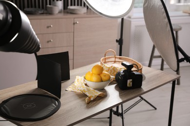 Photo of Professional camera and composition with ripe lemons on table in photo studio. Food photography