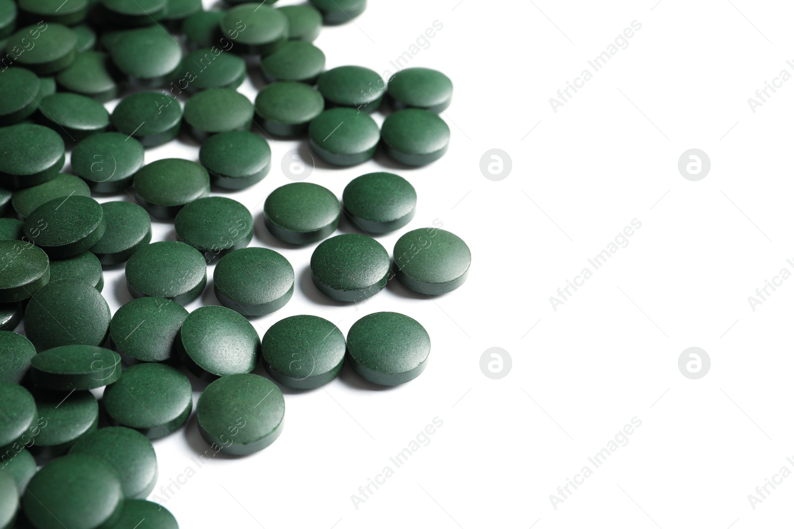 Photo of Green spirulina pills on white background. Alternative medicine