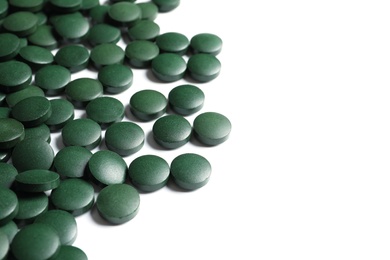 Photo of Green spirulina pills on white background. Alternative medicine