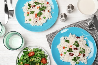 Photo of Boiled rice with vegetables served on wooden table, flat lay