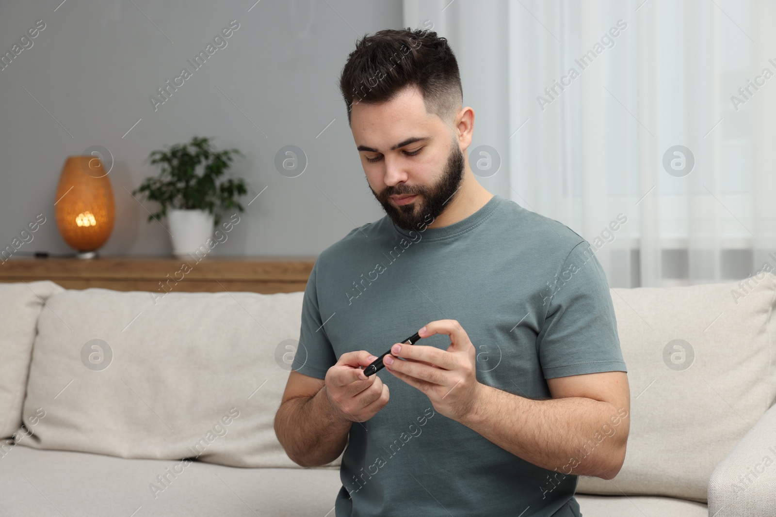 Photo of Diabetes test. Man checking blood sugar level with lancet pen at home