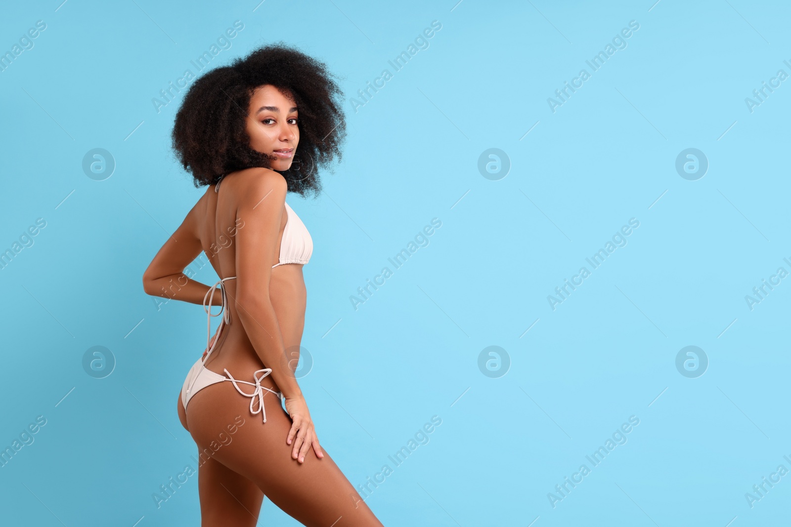 Photo of Beautiful woman in stylish bikini on light blue background, space for text