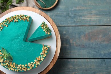 Photo of Flat lay composition with tasty spirulina cheesecake on blue wooden table, space for text