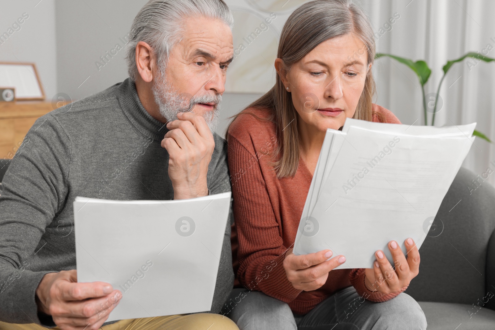 Photo of Elderly couple with papers discussing pension plan in room