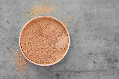 Photo of Face powder on grey textured table, top view. Space for text