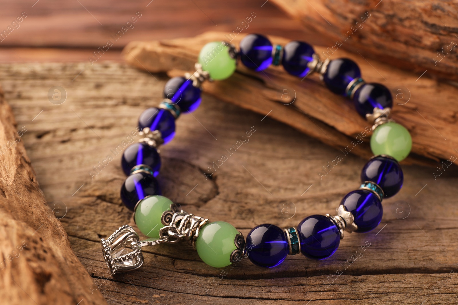 Photo of Stylish presentation of beautiful bracelet with gemstones on wooden table, closeup