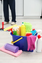 Different cleaning supplies in bucket and man mopping floor, selective focus