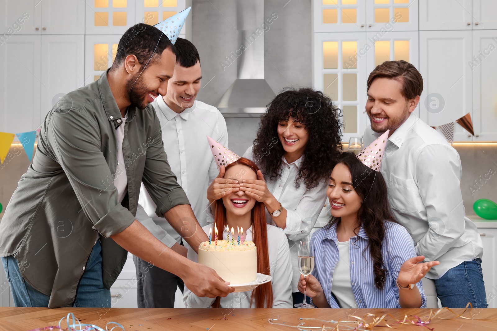 Photo of Happy friends with tasty cake celebrating birthday in kitchen