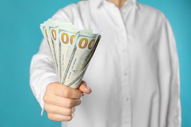 Photo of Woman holding dollar banknotes on turquoise background, closeup. Money exchange concept