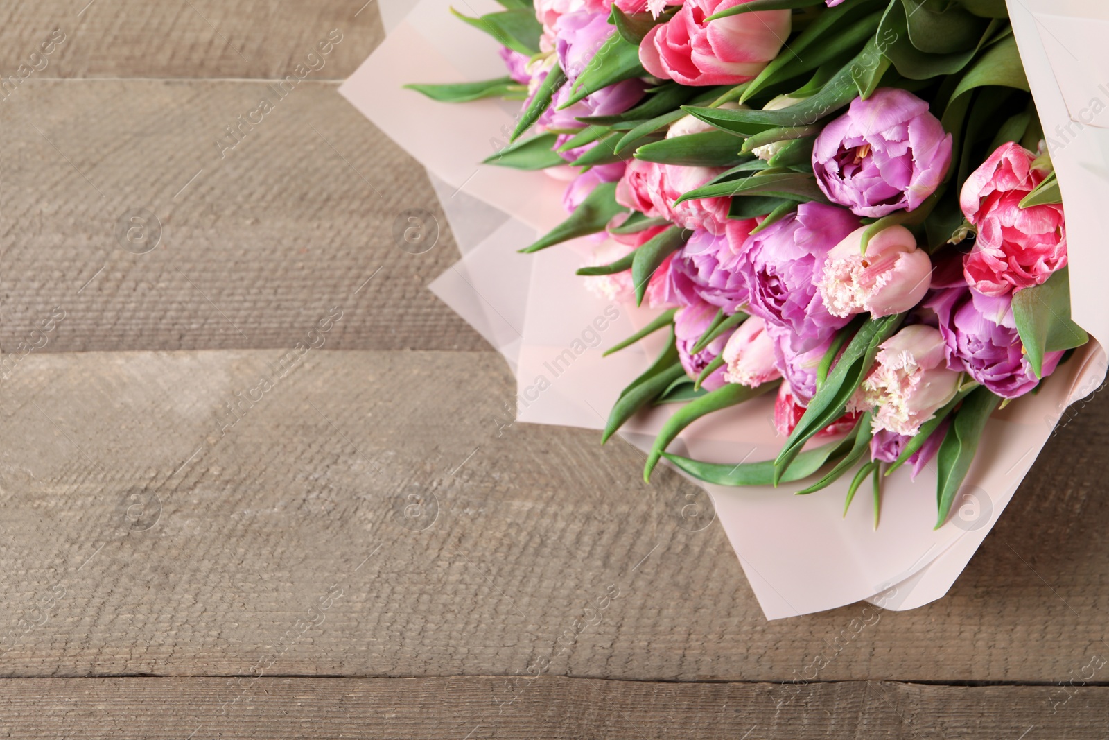 Photo of Bouquet of beautiful tulips on wooden table, closeup. Space for text