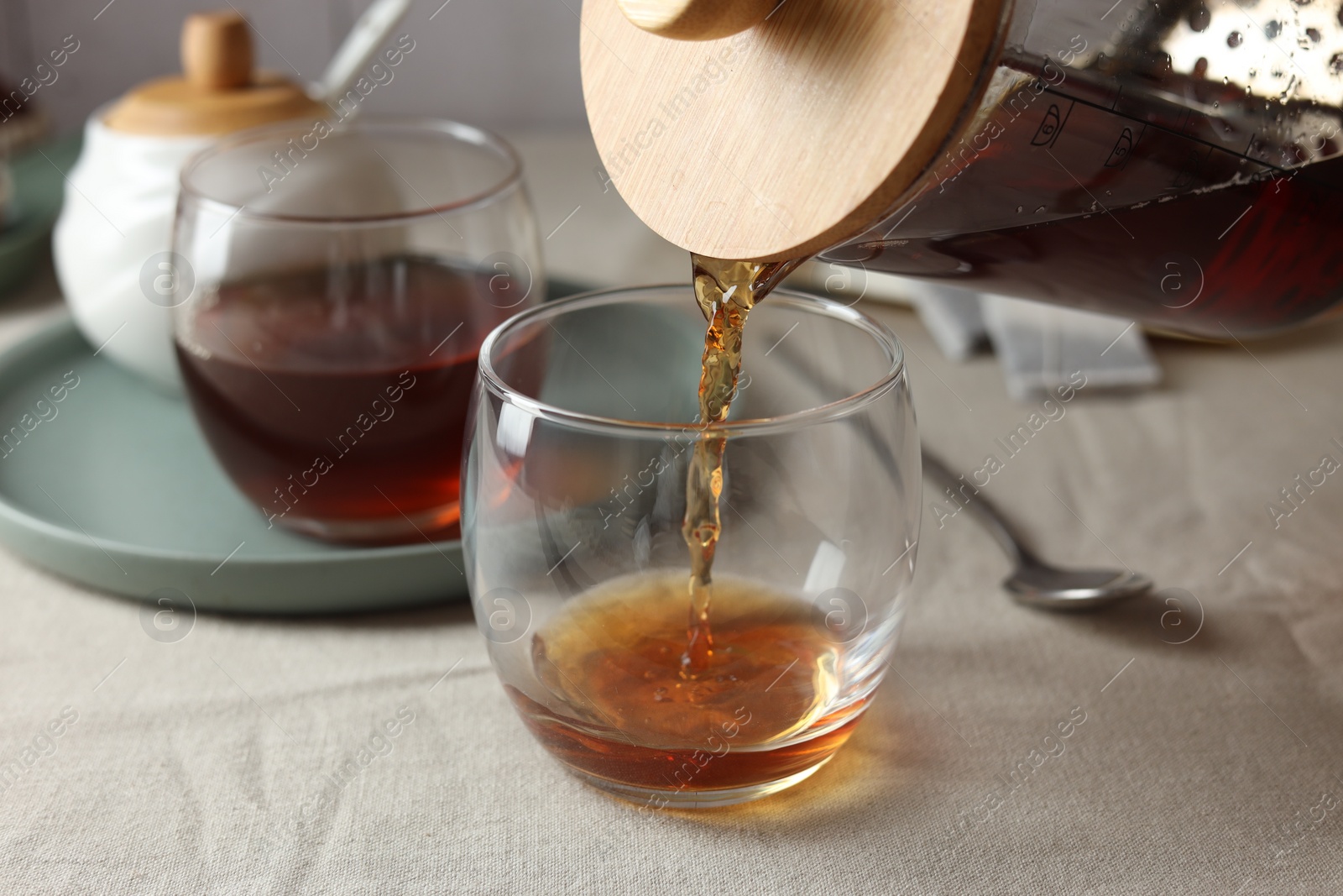 Photo of Pouring warm tea into cup on light table, closeup