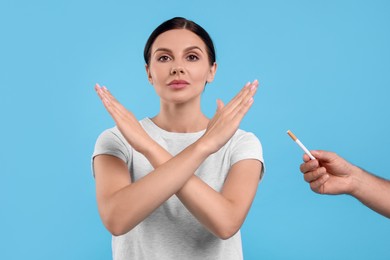 Photo of Stop smoking concept. Woman refusing cigarette on light blue background
