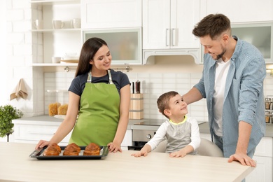 Photo of Woman treating family with oven baked buns at table in kitchen