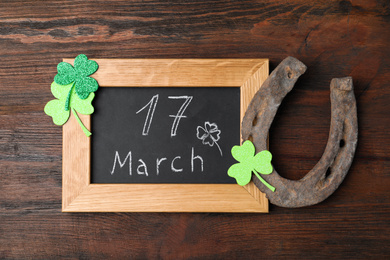 Photo of Flat lay composition with horseshoe and chalkboard on wooden background. St. Patrick's Day celebration