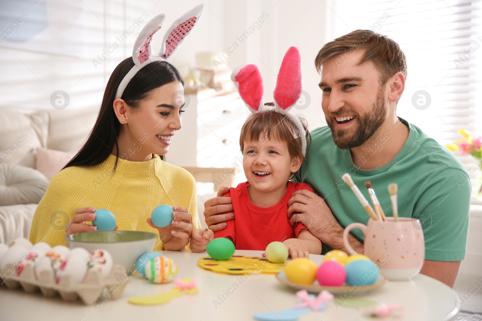 Photo of Happy family painting Easter eggs at table indoors