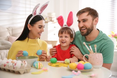 Happy family painting Easter eggs at table indoors