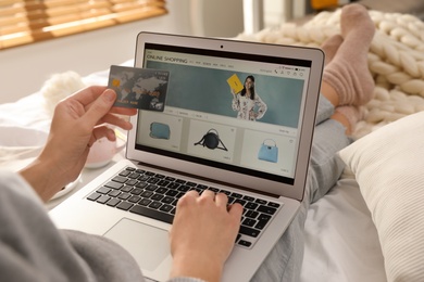 Photo of Woman with credit card using laptop for online shopping indoors, closeup
