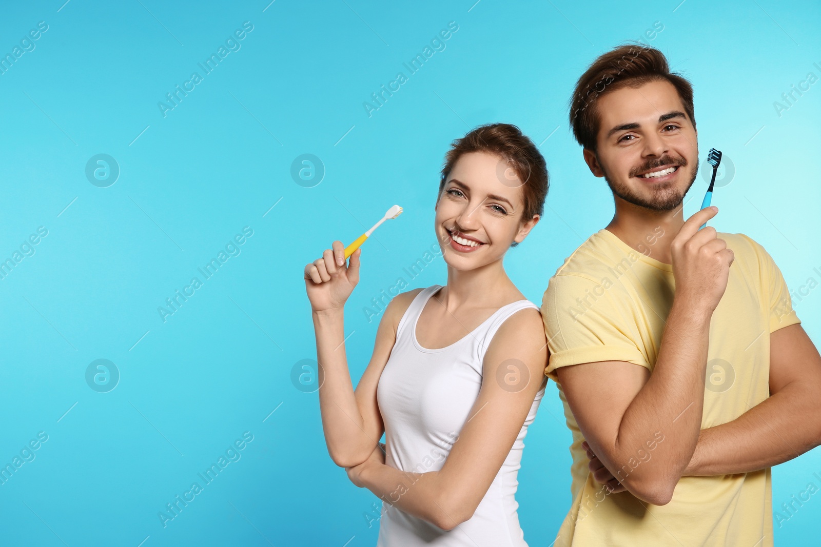 Photo of Portrait of young couple with toothbrushes on color background. Space for text