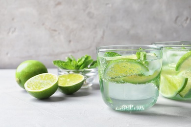 Refreshing beverage with mint and lime in glasses on table
