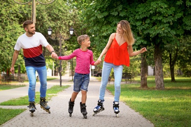 Photo of Young happy family roller skating in summer park