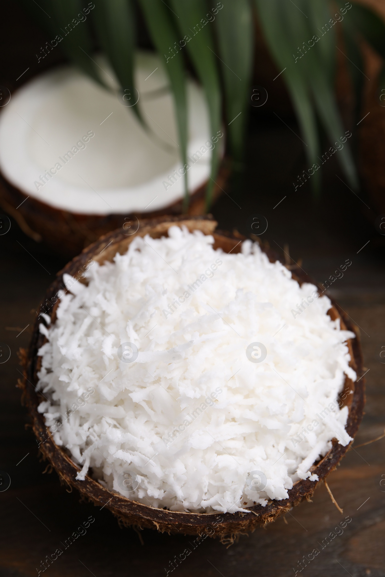 Photo of Coconut flakes in nut shell on wooden table