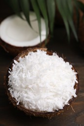 Photo of Coconut flakes in nut shell on wooden table