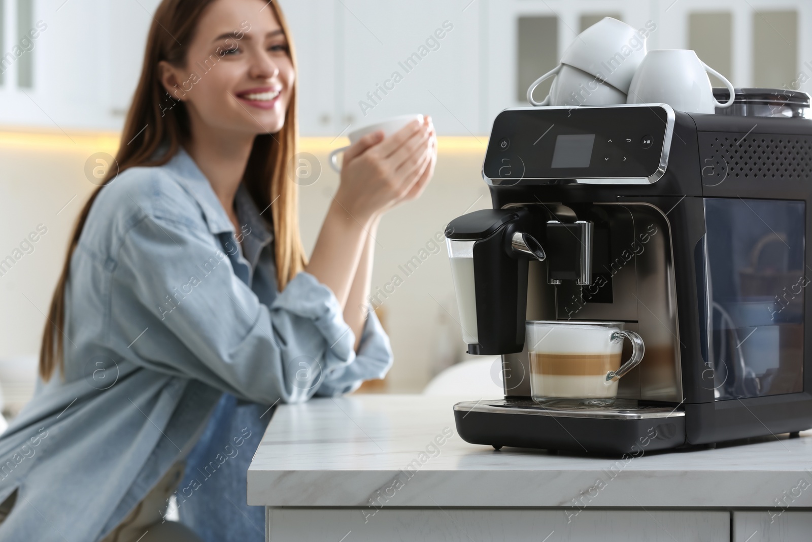 Photo of Young woman enjoying fresh aromatic coffee in kitchen, focus on modern machine