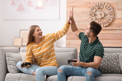 Emotional young couple playing video games at home