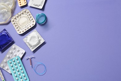 Contraceptive pills, condoms and intrauterine device on violet background, flat lay with space for text. Different birth control methods