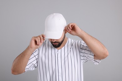 Man in stylish white baseball cap on light grey background