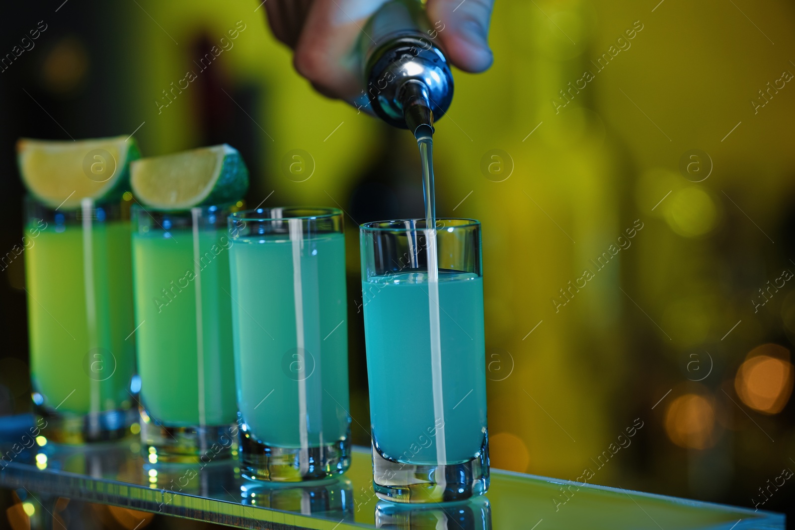 Photo of Bartender pouring alcohol drink into shot glass on blurred background, closeup. Space for text