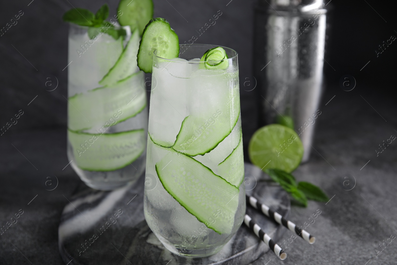 Photo of Refreshing cucumber water with ice on dark grey table