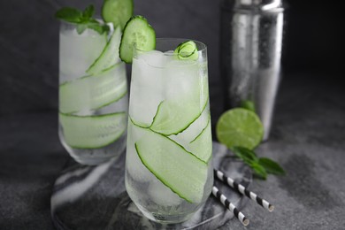 Refreshing cucumber water with ice on dark grey table