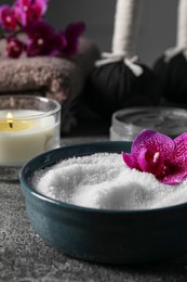 Photo of Beautiful composition with sea salt, burning candle, flowers and different spa products on grey table, closeup