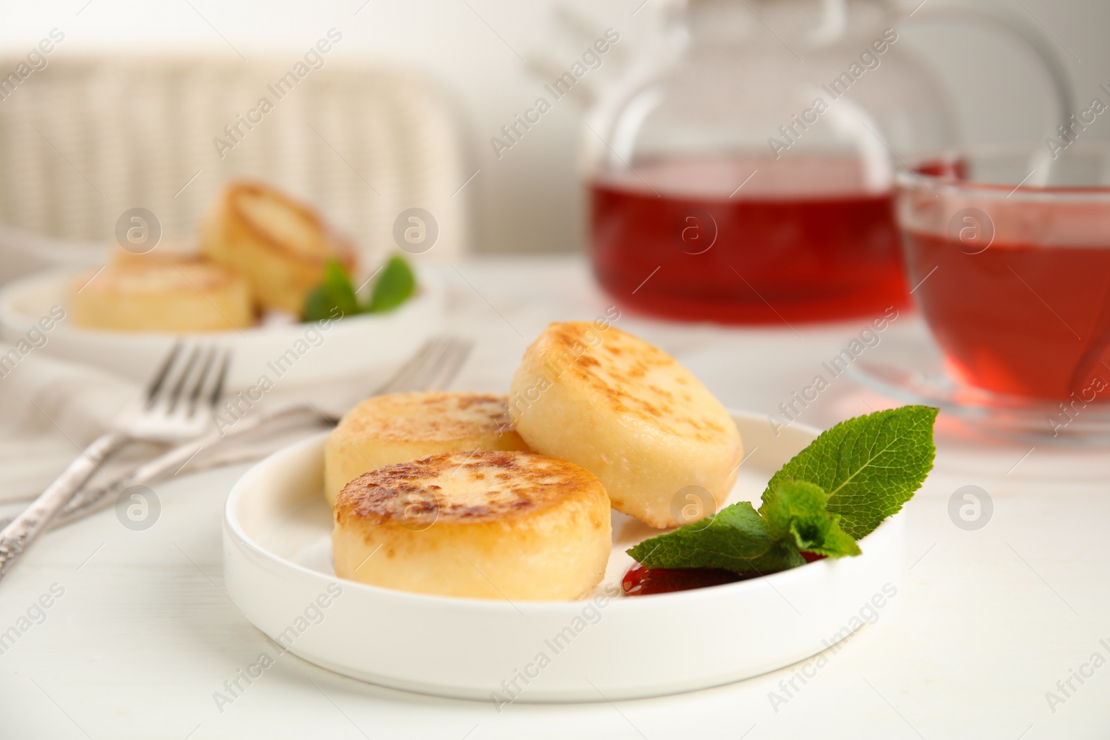 Photo of Delicious cottage cheese pancakes with jam and mint on white table