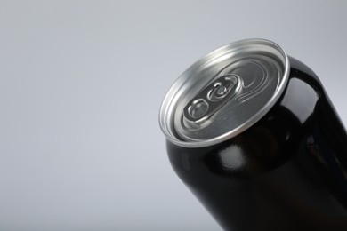 Black can of energy drink on light grey background, closeup. Space for text
