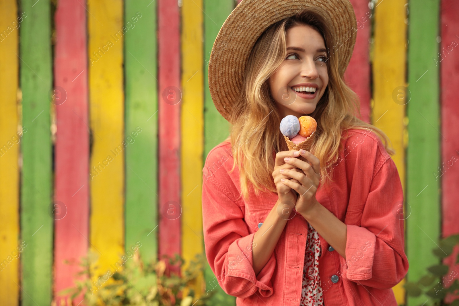 Photo of Happy young woman with delicious ice cream in waffle cone outdoors. Space for text