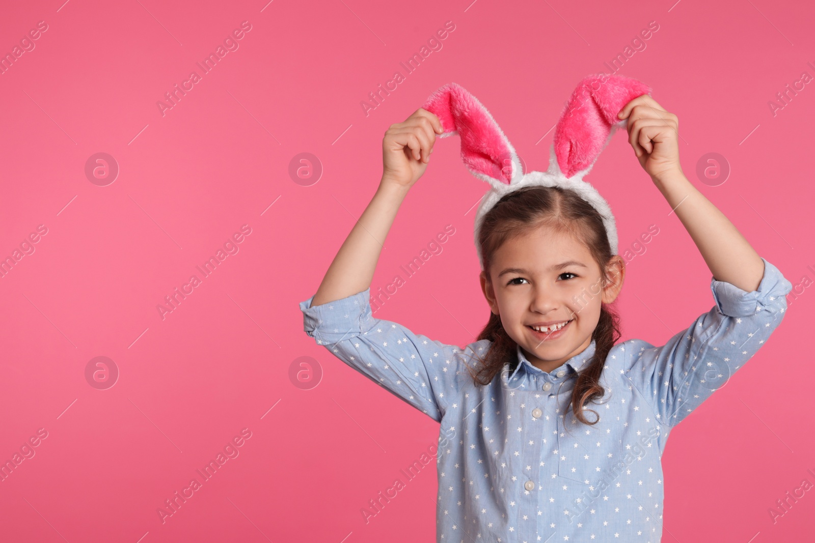 Photo of Portrait of little girl in Easter bunny ears headband on color background, space for text